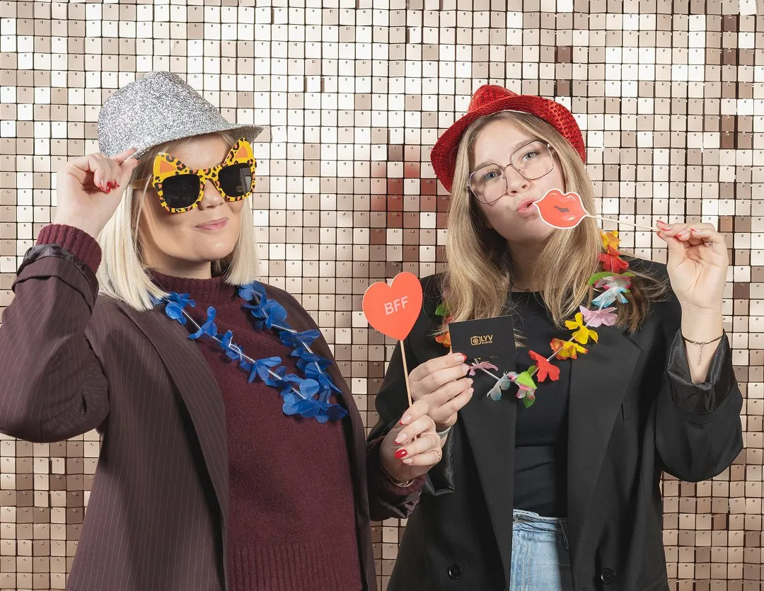 Twee gasten met props voor een paillettenwand